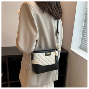 Detail of black and white quilted crossbody bag with gold metal chain and logo
