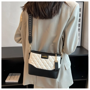 Macro detail of bicolored quilted leather bag with brand plaque and geometric wide strap