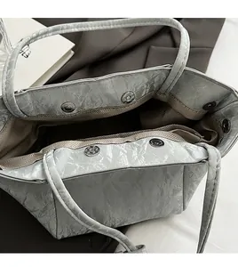 Dettaglio interno borsa a secchiello grigia con chiusure magnetiche e fodera a spina di pesce