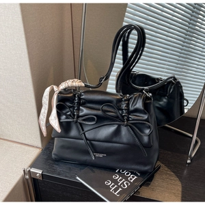 Close-up of black leather tote with ribbon bow detail and heart pattern silk scarf