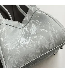 Dettaglio del tessuto metallico argento e dei piedini protettivi sul fondo della borsa