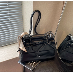 Close-up of black PU tote bag with bow details and heart-print silk scarf on its handle