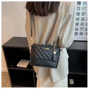 Detailed close-up of a quilted black bucket bag with golden logo and fabric strap