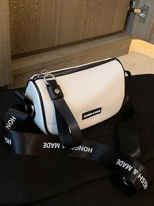 White cylinder crossbody bag with black logo strap shown from a top-down diagonal angle