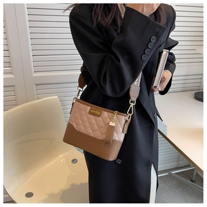 Detail of quilted leather bucket bag with brand metal logo and wide woven strap