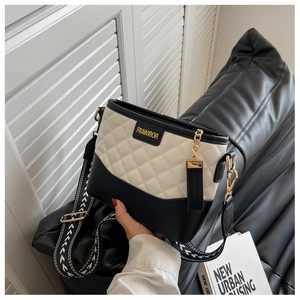 Detail of two-tone bucket bag featuring diamond quilted texture and wide woven strap
