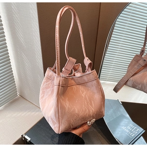 Dettaglio della borsa a secchiello rosa chiaro con trama marmorea e manici lunghi