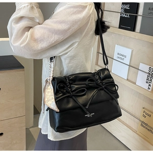 Detail of black tote bag featuring decorative bows and printed silk scarf on shoulder strap