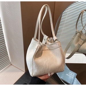 Dettaglio di una borsa a secchiello color crema con coulisse e cuciture artigianali