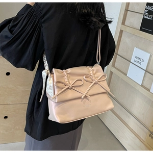 Detail of soft cream-pink tote bag featuring twin bows and a heart-print silk scarf accessory