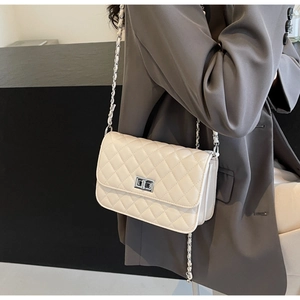 Detailansicht der cremefarbenen Stepptasche mit silbernem Drehverschluss und Kettenriemen