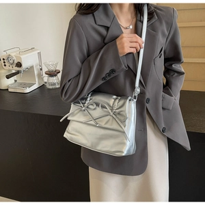 Silver tote bag detail with bow accents and metallic finish shown with a casual blazer