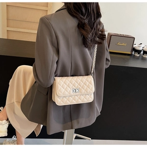 Detailansicht der beigefarbenen Stepptasche mit silbernem Drehverschluss an einem Model