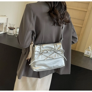 Detail of silver metallic tote bag with decorative bows and a heart print silk scarf