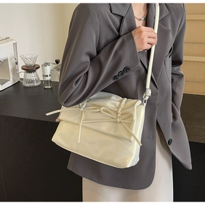 Detail of cream PU leather tote bag featuring elegant bow accents and fashion text