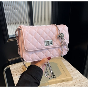 Detail einer hellrosa gesteppten Handtasche mit Silberkette und Metallkugel-Anhänger