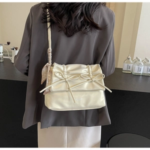 Detail of cream pleated shoulder bag with 3D bows and heart pattern scarf on model