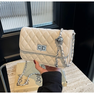 Detailansicht der cremefarbenen Stepptasche mit Silberkette und Metallkugel-Versteller