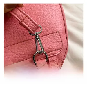 Macro shot of silver metal swivel hook and D-ring on pink lychee grain leather bag
