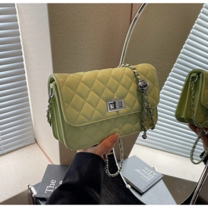 Detail der hellgrünen Stepptasche mit silberner Kette und floralem Kugelanhänger