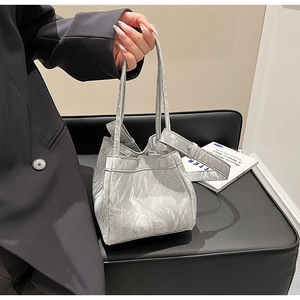 Dettaglio della borsa a secchiello argento metallizzato con texture plissettata unica