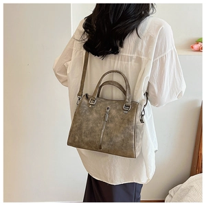 Detail of vintage brown tote bag showing textured PU leather and decorative zipper details
