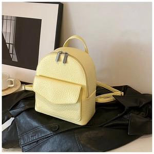 Detail of a bright yellow mini backpack in pebble leather on a stylish black leather jacket
