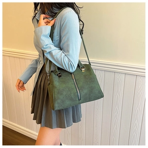 Detail of vintage green leather tote bag featuring metal zipper and dual top handles