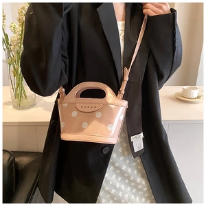 Pink polka dot bucket bag with leather trim and adjustable strap shown on model