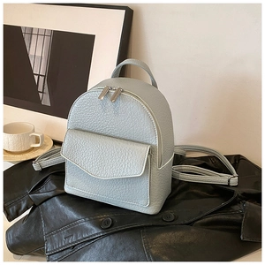 Close-up of light grey pleated backpack showing litchi leather texture and silver hardware