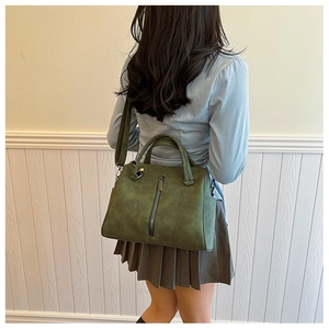 Back view of model carrying a vintage olive green tote bag with adjustable shoulder strap