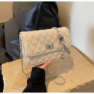 Detail der cremefarbenen Stepptasche mit silberner Kette und Kugelverzierung