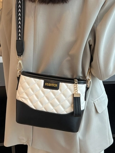Quilted black and white bucket bag with a patterned wide strap and gold hardware
