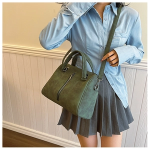 Detail of forest green tote bag with dual handles and metal zipper on model