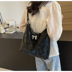 Détail du sac cabas noir mat avec nœud argenté et bandoulière en chaîne métallique