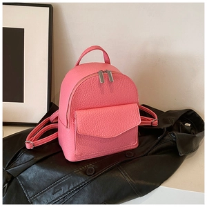 Detailed macro of pink pebbled leather mini backpack with silver zippers on black background