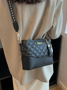 Quilted black bucket bag with a wide patterned strap and elegant tassel detail
