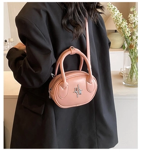 Detailed view of pink leather crossbody bag with silver hardware on a model back