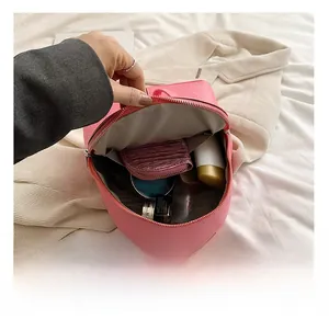 Internal storage of a pink leather mini backpack showing wallet and cosmetics items
