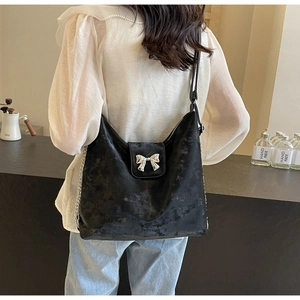 Détail du sac cabas en similicuir noir avec nœud argenté porté au dos d'un modèle