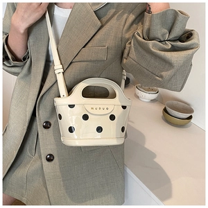 Close-up of beige polka dot bucket bag with glossy finish and delicate brand lettering