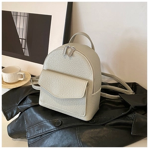 Detail of beige lychee grain leather mini backpack with silver zippers and front pocket