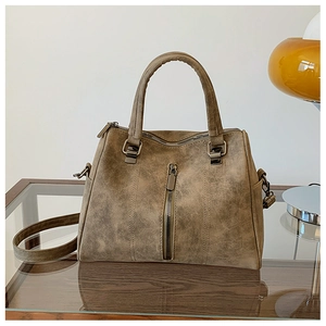 Close-up of retro brown tote bag with matte texture and metallic zipper details on desk