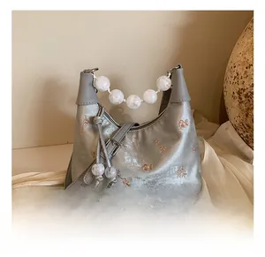 Detail of silver satin Boston bag featuring floral embroidery and marble bead handle