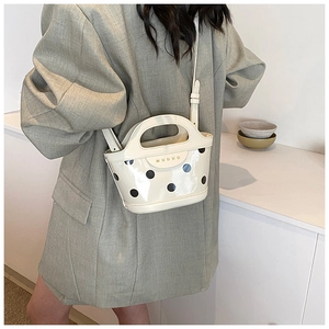 Close-up of cream polka dot patent leather crossbody bag with gold metal logo detail