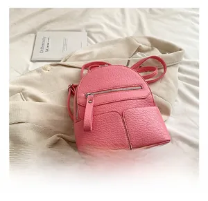 Detail view of pink pebbled leather mini backpack with front zipper and side pockets