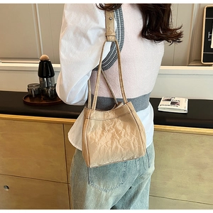 Dettaglio della borsa a tracolla plissettata beige con texture eleganti in scena lifestyle