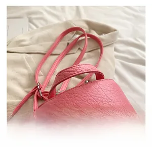 Detail of pink pebbled leather mini backpack showing reinforced handle and silver zipper