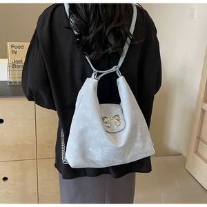 Gros plan du sac fourre-tout bleu clair avec boucle nœud argentée et texture moirée