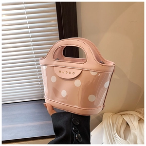 Detail view of pink polka dot handbag with clear PVC outer layer and leather handles